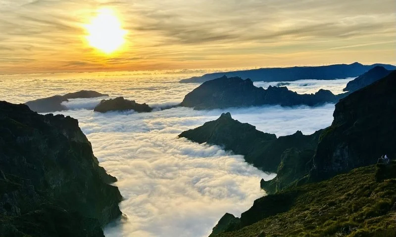 Górskie szczyty wystające z chmur na tle zachodu słońca